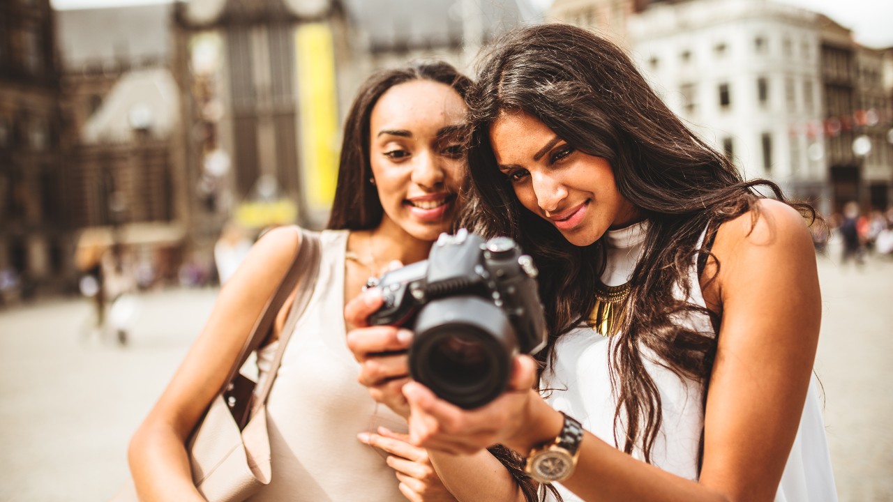 Two female travellers looking at pictures on camera; image used for HSBC home and Away page